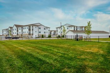 A large grassy field in front of apartment buildings.